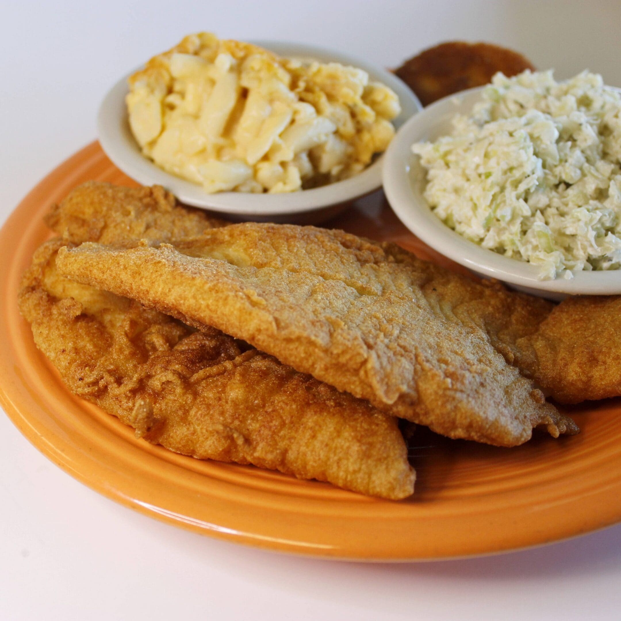 Fried fish with coleslaw and potato salad